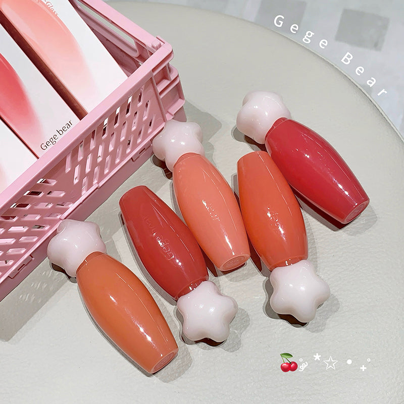 Set of lip glosses with a pink basket on a light background, featuring the brand 'Gege Bear'.