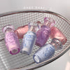 Set of pastel-colored glass bottles with decorative labels on a metal wire rack.