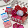 Basket with pink and red containers and 'Gege Bear' boxes on a white surface