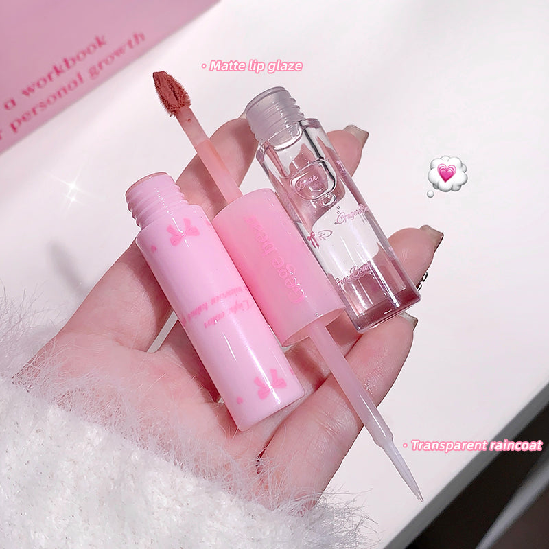 Pink lip gloss and applicator held by a hand on a white surface