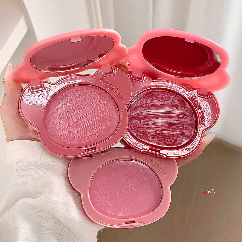 Pink blush compact with three shades held by a hand against a neutral background