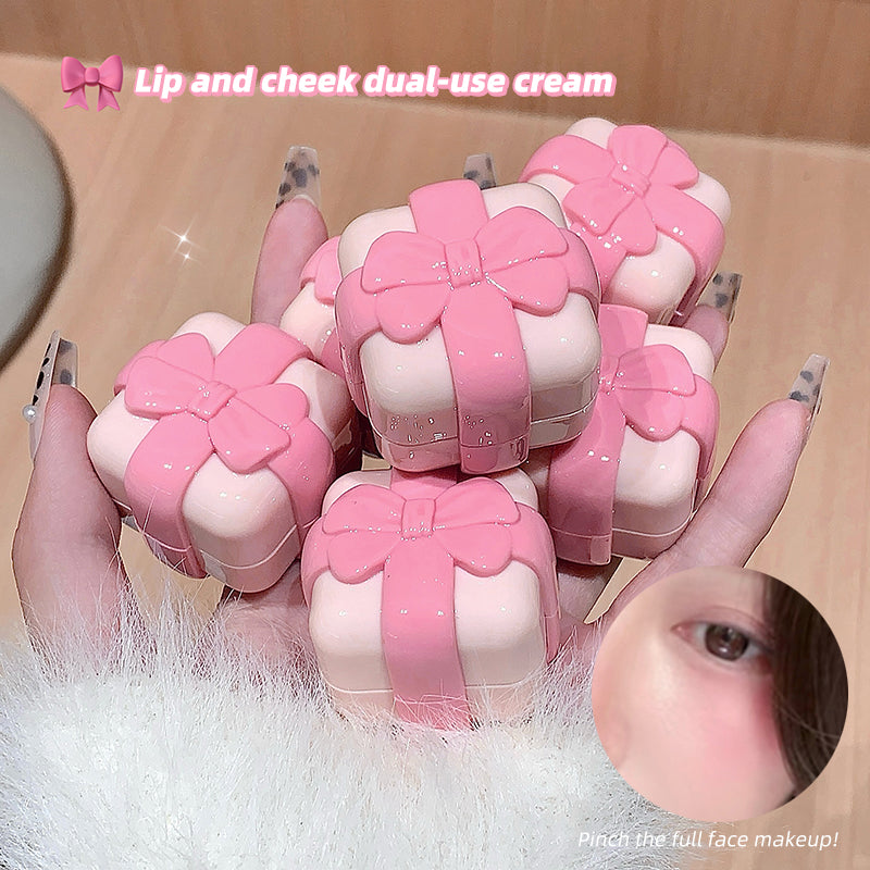 Pink lip and cheek dual-use cream with decorative bows held by a hand.