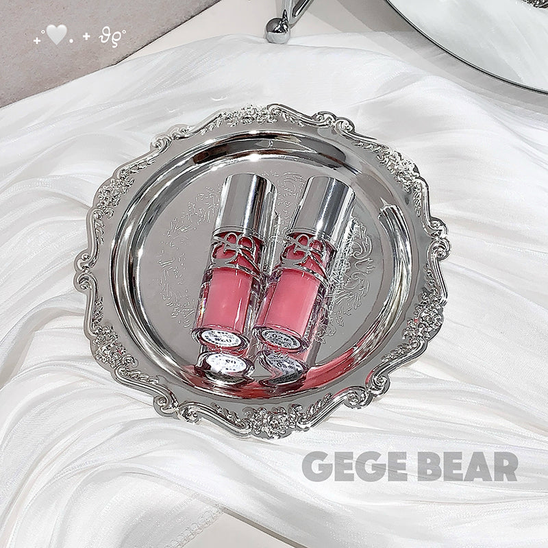 Two pink lip glosses on a silver tray with 'GEGE BEAR' branding.