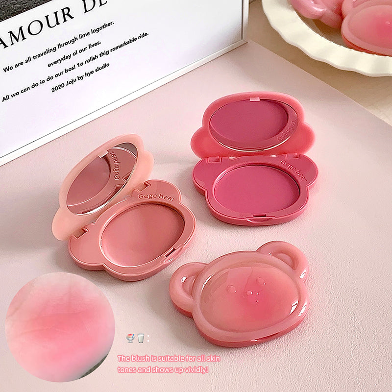 Pink blush compact with mirror and pink blush on a light pink surface.