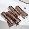 Set of four transparent brown glass containers on a white surface
