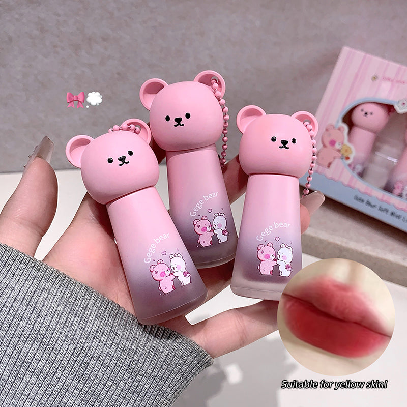 Three pink bear-shaped lip balms held by a hand, with a close-up of a lip and text 'Suitable for yellow skin' on a light gray background.