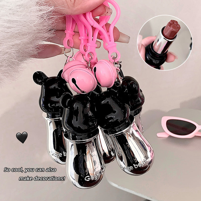 Black and pink lip balm keychain held by a hand with sunglasses and lipstick in the background.