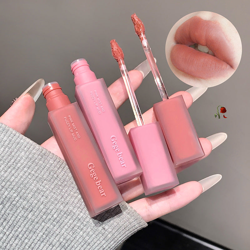 Hand holding four lip glosses with close-up of lips wearing a pink lip color.