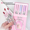 Set of pink and white pens with a decorative box featuring a cat illustration, held by a hand.