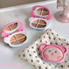 Three small makeup palettes with cartoon designs on a white surface.