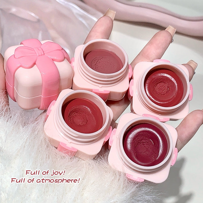 Pink lip balm containers with a hand holding them on a white background