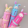 Three colorful lip balm containers with cartoon character designs held by a hand against a neutral background.