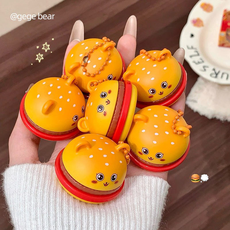 Hand holding a set of cute yellow and red toy buns with cartoon faces on a wooden surface.