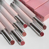 Set of pink lipsticks with silver caps on a light gray background