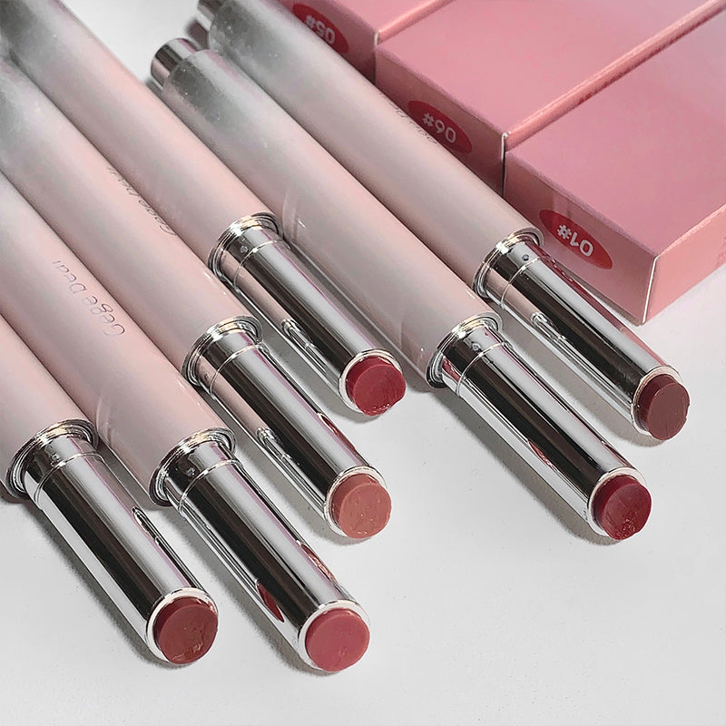 Set of pink lipsticks with silver caps on a light gray background