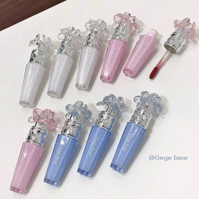 Set of colorful lip glosses with decorative caps on a white surface.