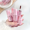 Set of pink lip products with a hand holding one, on a light background