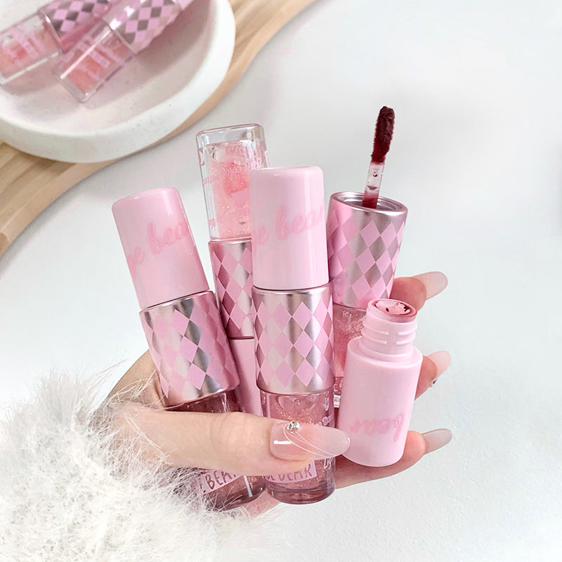 Set of pink lip products with a hand holding one, on a light background