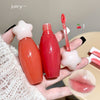 Two red lip glosses held in a hand with cherry graphics and 'juicy' text.