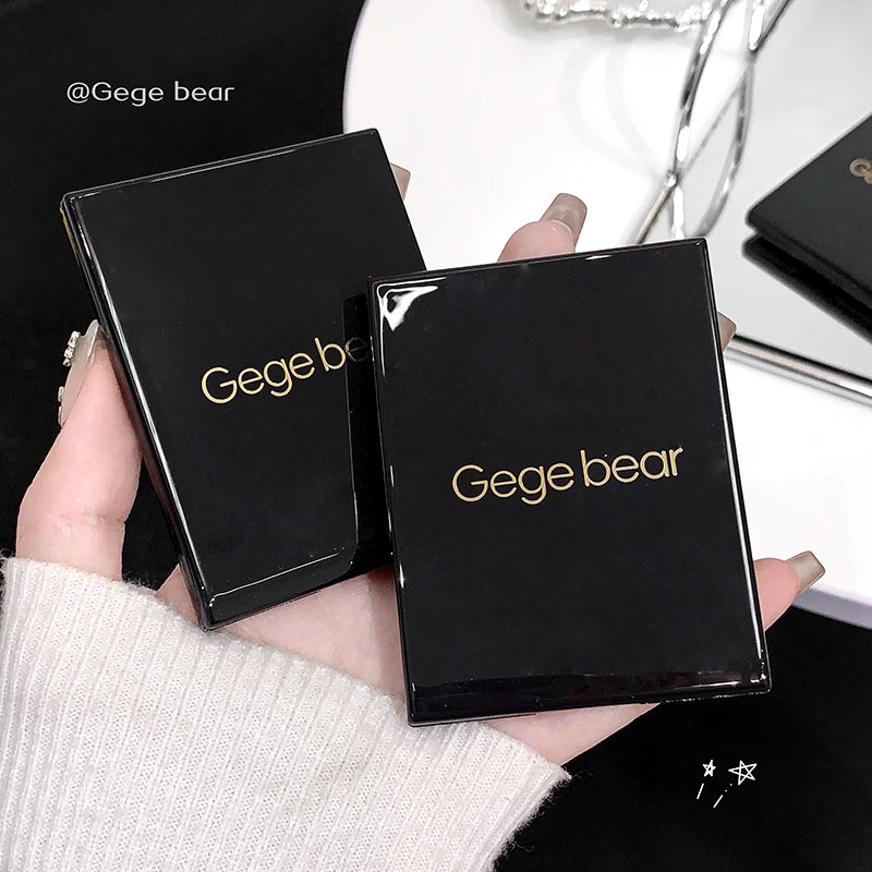 Two black compact cases with 'Gegebear' branding held by a person.