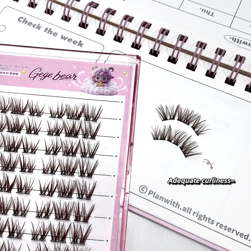 False eyelashes on a pink display card with a planner in the background