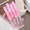 Set of pink lip glosses held in a hand with a blurred background