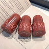 Three red lip balm tubes with 'GEGE BEAR' branding on a surface with text.