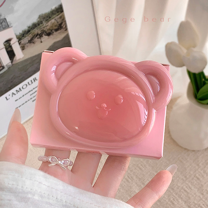 Pink bear-shaped container held in a hand with a blurred background