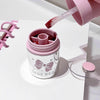 Pink lip balm being applied to a container with 'GEGE.BEAR' branding on a white surface.