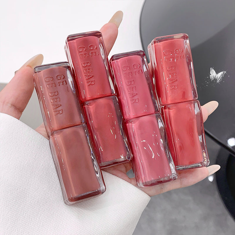 Hand holding six lip glosses with 'BE BEAR' branding.