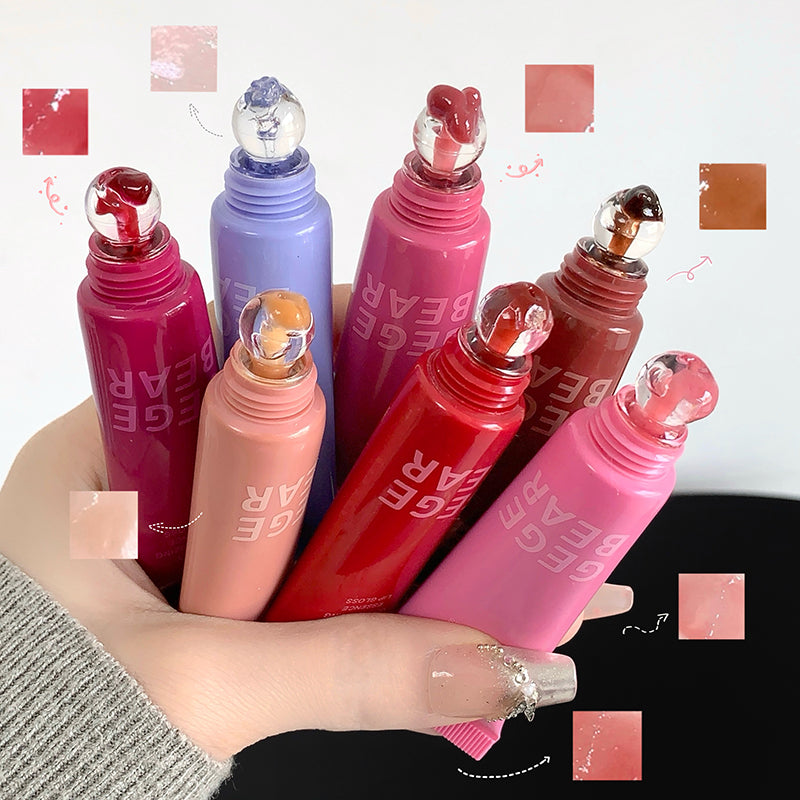 Collection of colorful lip glosses with visible brand name held by a hand.