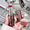 Lipstick held by a hand with a close-up of lips shown, on a reflective surface.