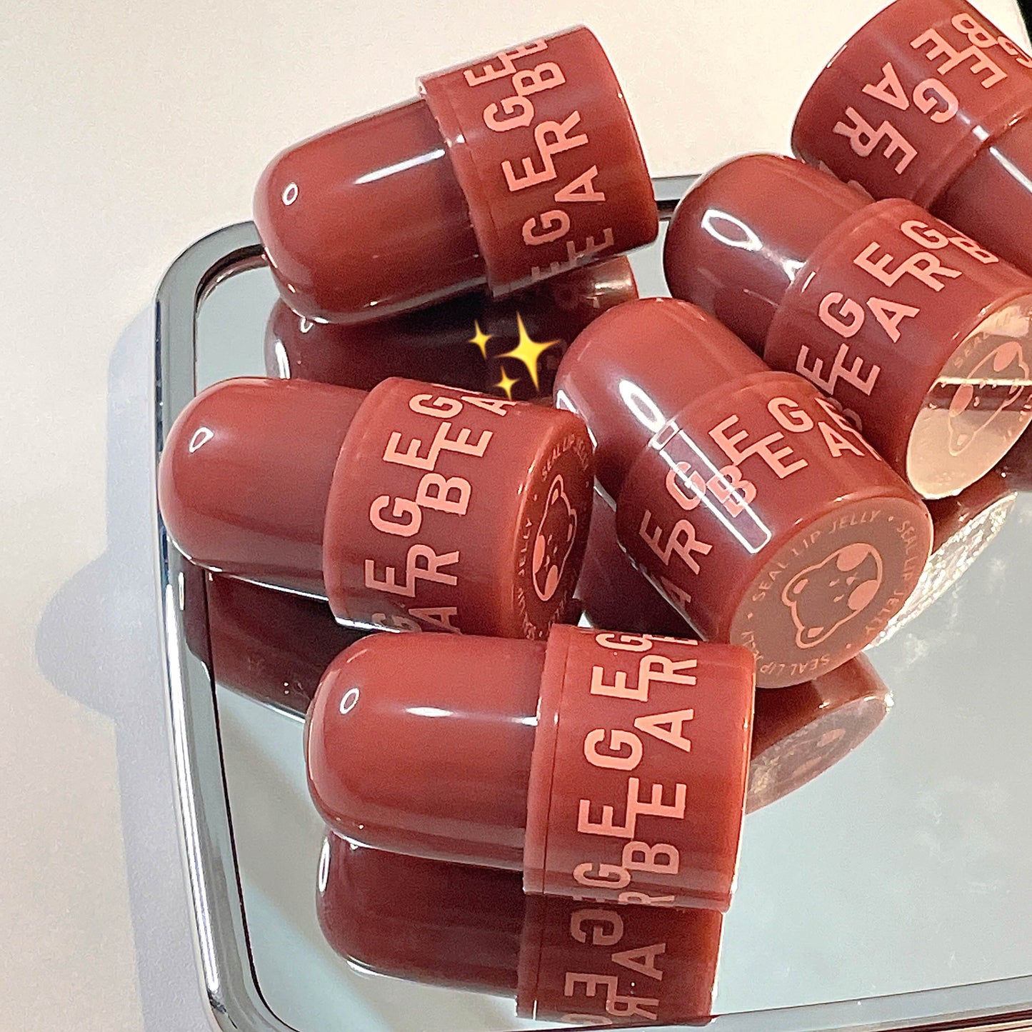 Red lip gloss bottles with 'Rage Bear' branding on a reflective surface.
