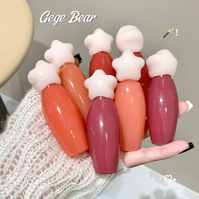 Set of colorful lip glosses with star-shaped tops held by a hand.