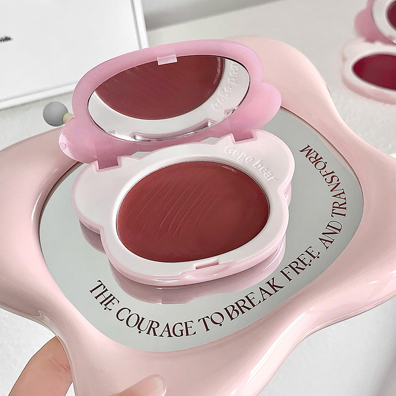 Pink makeup compact with a mirror and lip balm on a light background