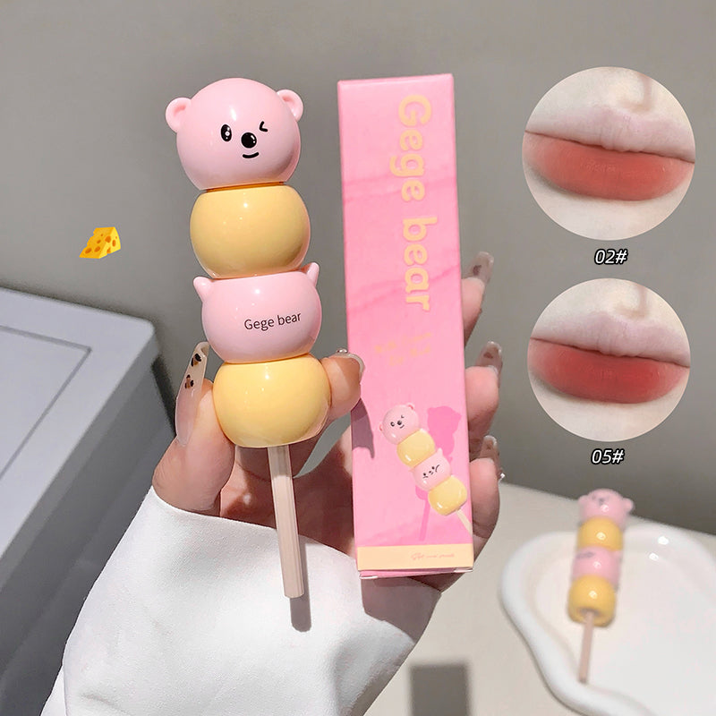 Pink and yellow bear-shaped lip balm with packaging on a neutral background