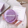 Purple compact powder with 'Gege Bear' branding held by a hand on a light background
