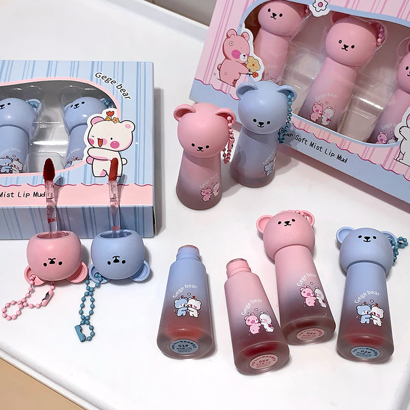 Set of cute bear-shaped lip balms with packaging on a white surface
