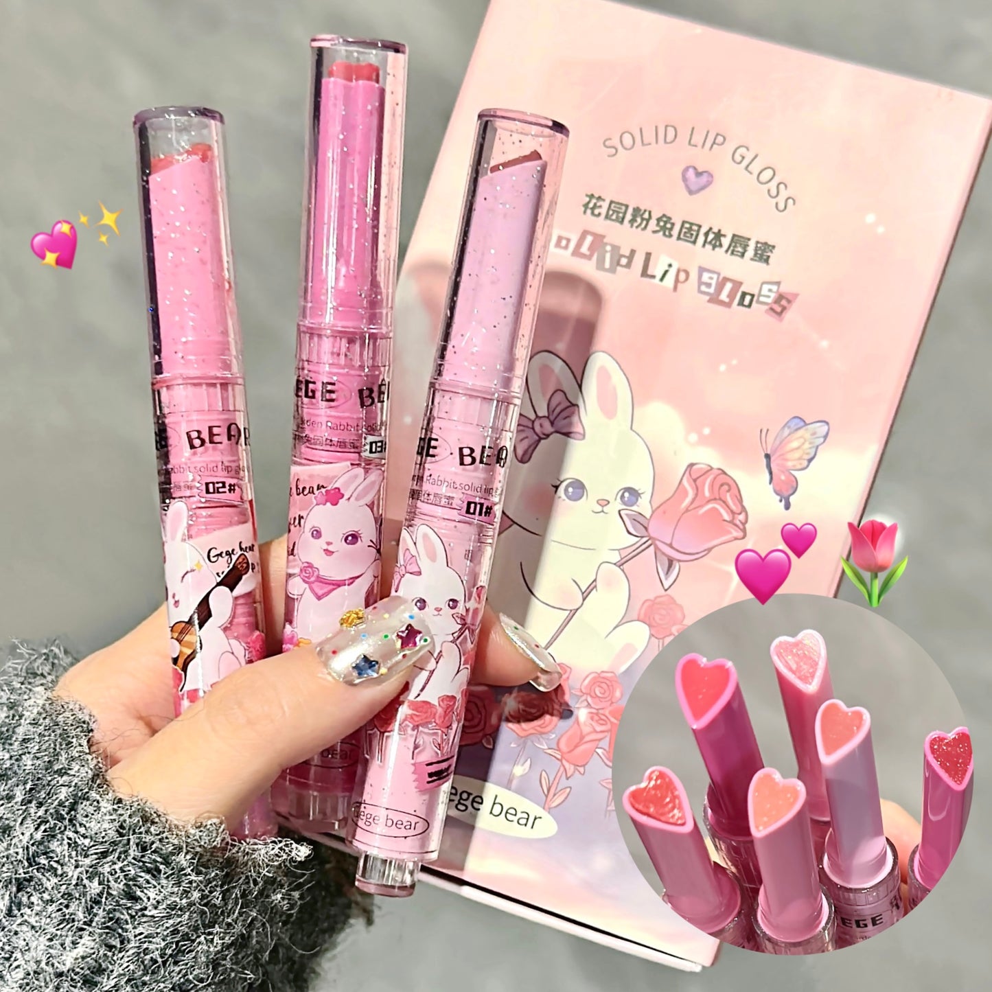 Pink lip gloss with cartoon packaging held by a hand, on a gray background.