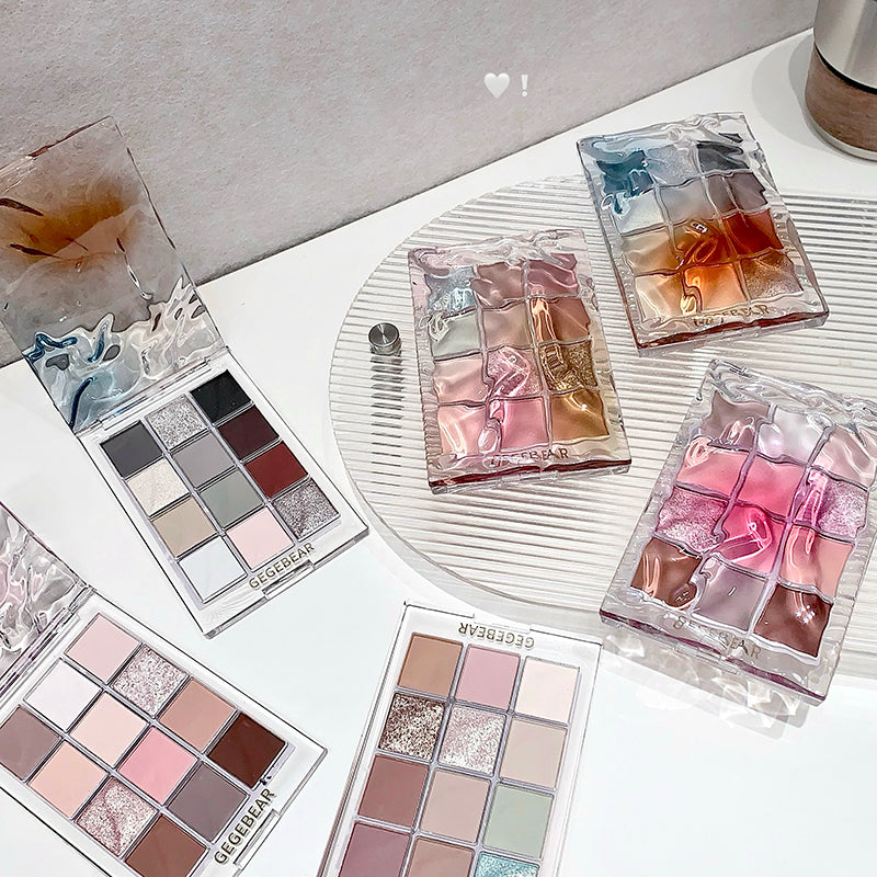 Collection of makeup palettes on a white surface with a heart emoji in the background