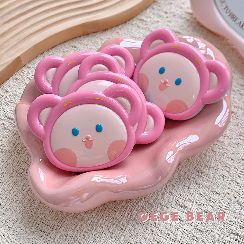 Pink cartoonish container with bear faces on a textured beige surface, featuring the brand 'GEGE BEAR'.