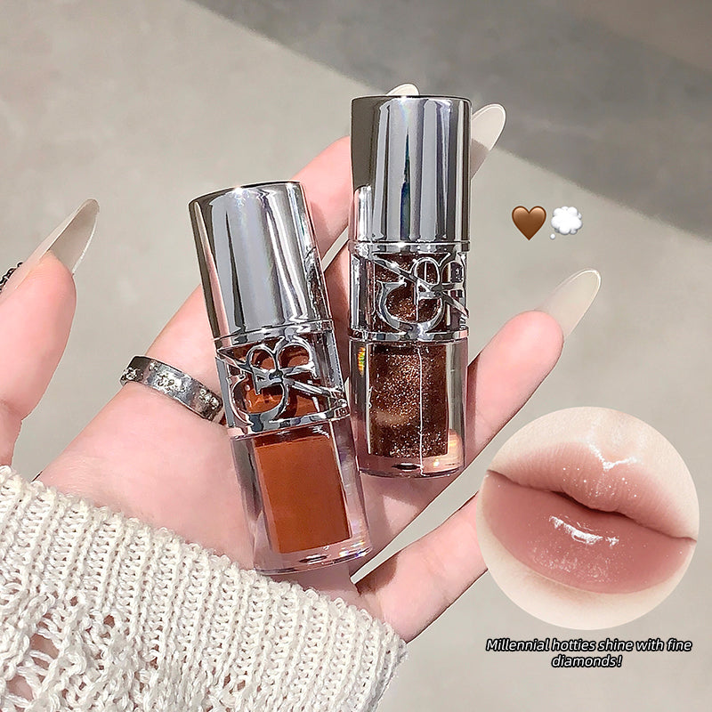 Two lip glosses held by a hand with a close-up of a glossy lip.