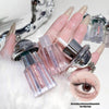 Close-up of a hand with glittery nails holding lip glosses, with a blurred background.