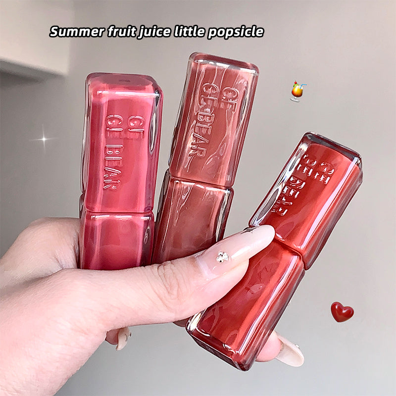 Three red lip glosses held by a hand with a neutral background