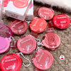Multiple GEGBEAR lip products on a textured surface with packaging in the background.