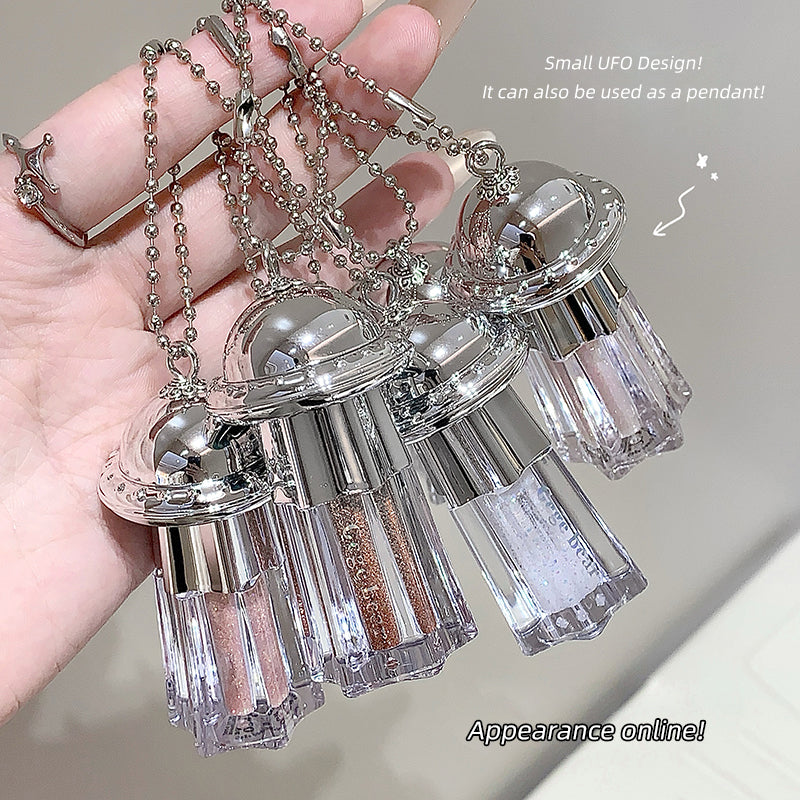 Small UFO design pendant held in a hand with a blurred background