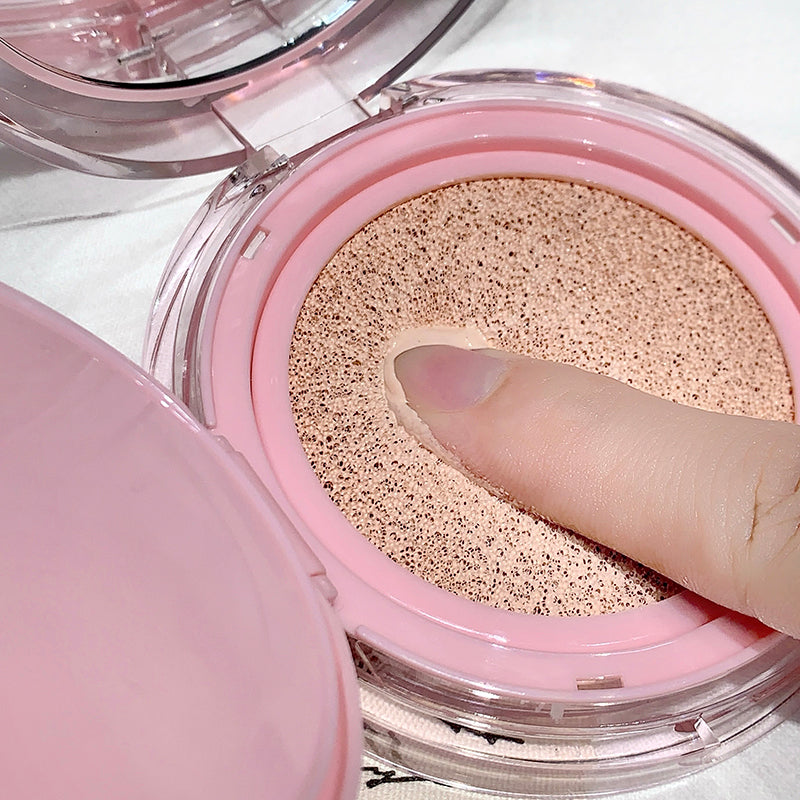 Open pink compact with a finger pressing on the powder inside