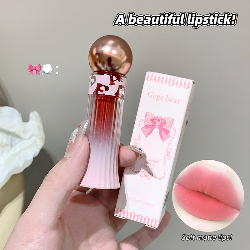 Lipstick with pink and red gradient and gold cap, held by a hand, with packaging and close-up of lips shown.