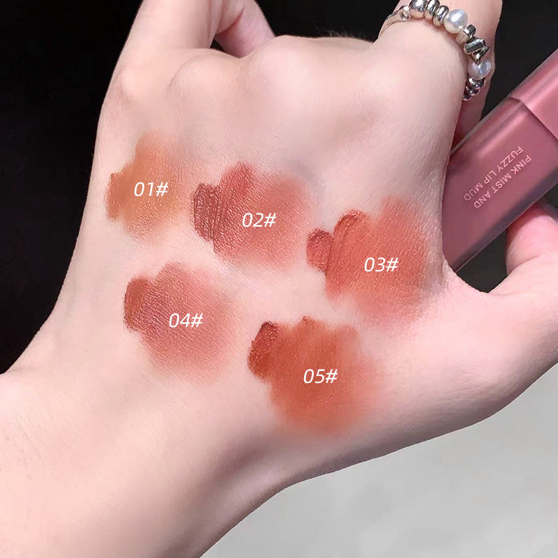 Hand with five different shades of lipstick swatched on a dark background
