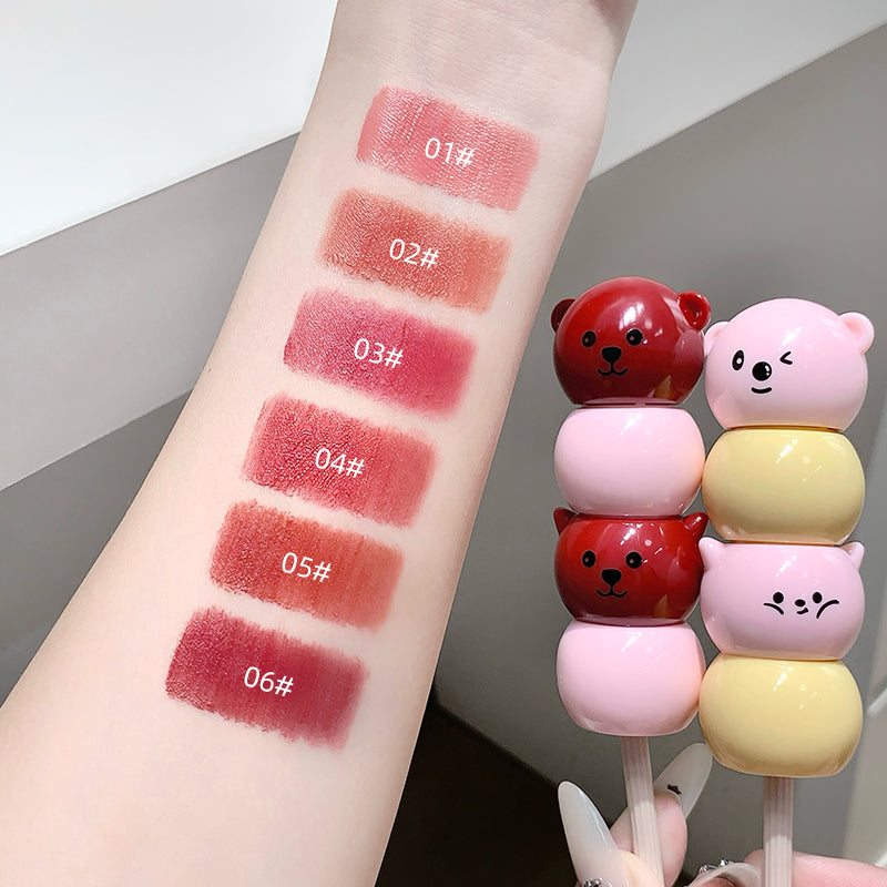 Lipstick swatches on a arm with colorful bear-shaped objects next to it.